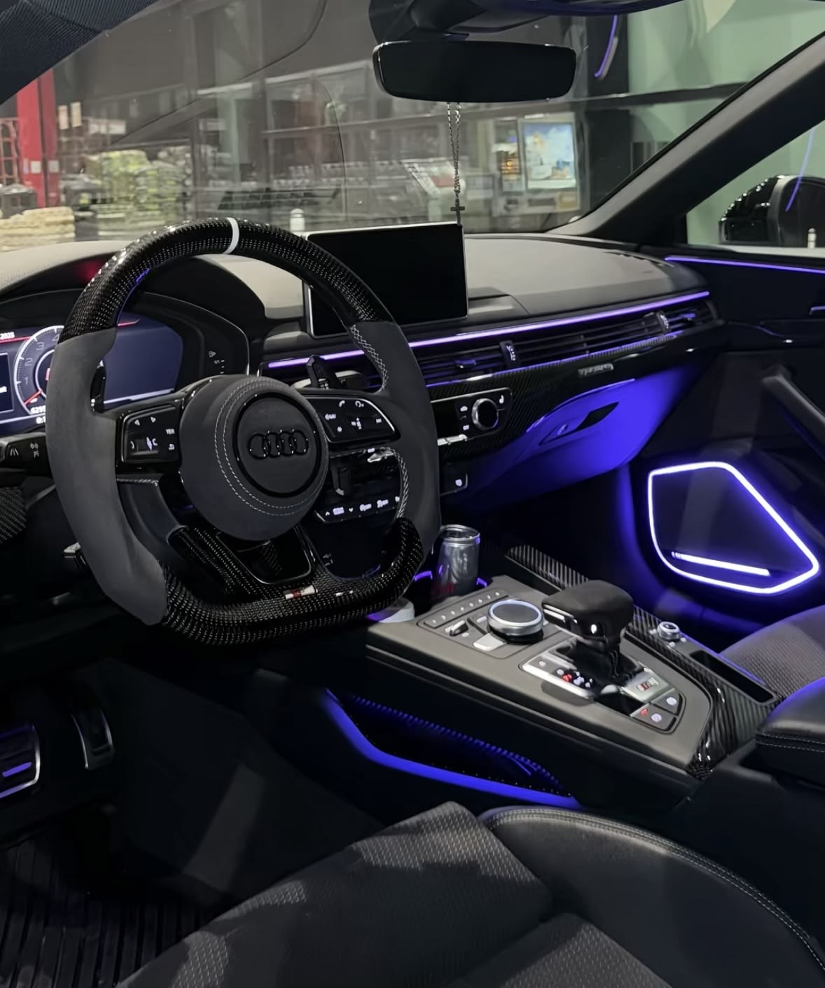 Blue ambient lighting on the vents, console and door panel of an Audi interior