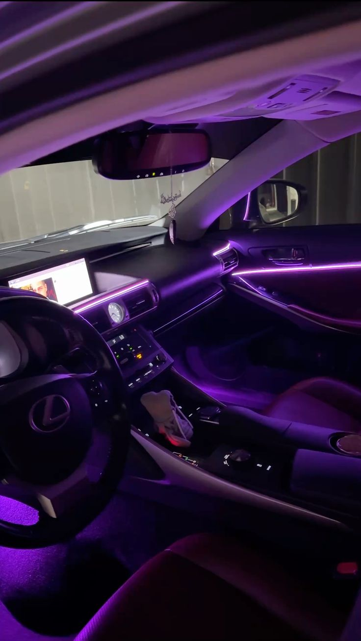 Purple ambient light line across the dash and door card of a Lexus cabin at night